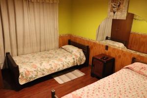 a small room with two beds and a mirror at Hostal Valle Central San Fernando, Chile in San Fernando