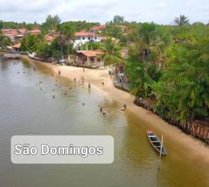 uma praia com pessoas e um barco na água em Chalé da Ana- com cozinha a 80 metros do Rio Preguiça em Barreirinhas