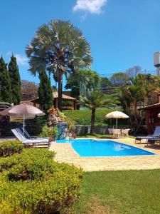 uma piscina com duas cadeiras e guarda-sóis num quintal em Pousada Vale do Café em Bueno Brandão