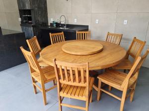 una mesa de madera con sillas de madera y una cocina en Casa - Recanto do Alesson, en Olímpia