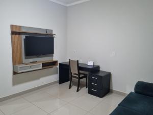 a living room with a desk with a tv and a chair at Casa - Recanto do Alesson in Olímpia