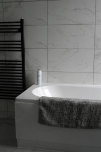 una vasca da bagno bianca con una bottiglia di sapone di EXECUTIVE APARTMENTS free on-site parking, 2 en-suites, sleeps 4, a Swindon
