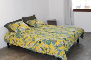 ein Bett mit einer gelben Decke und Kissen darauf in der Unterkunft Villa Émeraude - Piscine privée sans vis à vis in Rémire-Camp