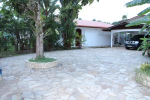 une allée en pierre avec un arbre en face d'une maison dans l'établissement Villa Émeraude - Piscine privée sans vis à vis, à Rémire-Camp