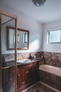 a bathroom with a sink and a tub and a mirror at High Grange Luxury Mountain Retreat - Pool, Spa, Sauna in Kalorama