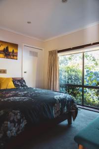 1 dormitorio con cama y ventana grande en High Grange Luxury Mountain Retreat - Pool, Spa, Sauna en Kalorama