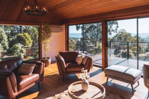 sala de estar con muebles de cuero y ventanas grandes. en High Grange Luxury Mountain Retreat - Pool, Spa, Sauna en Kalorama