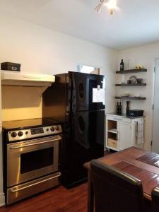 a kitchen with a stainless steel stove and refrigerator at Logement avec stationnement tennis et piscine in Saguenay