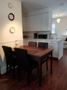 a kitchen with a wooden table and chairs and a kitchen with white cabinets at Logement avec stationnement tennis et piscine in Saguenay