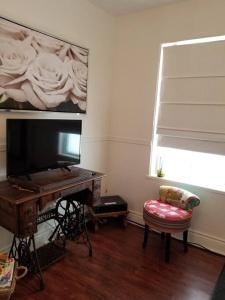 a living room with a desk with a television and a chair at Logement avec stationnement tennis et piscine in Saguenay