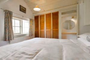 a large white bed in a bedroom with a window at Countryside Bliss: Historic Cottage by the Sea in Burgh Haamstede