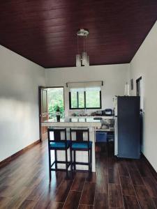 eine Küche mit einer Theke mit 2 Stühlen und einem Kühlschrank in der Unterkunft Villa Marina, Nosara in Río Seco