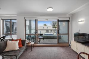a living room with a couch and a tv at Anchorage Oasis - Mt Maunganui Holiday Apartment in Mount Maunganui