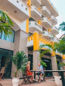 Un uomo e una donna seduti a un tavolo di fronte a un edificio di Sea and Sand Hotel a Hoi An