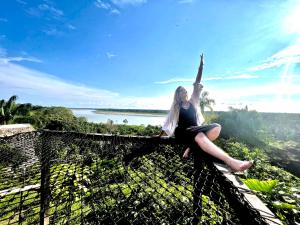 una mujer sentada en la parte superior de una valla con su brazo en el aire en Reserva Natural Natura Park en Puerto Nariño