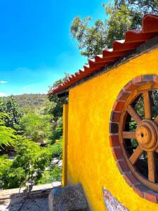 um edifício amarelo com uma roda de madeira em Posada Siete Nogales Tecozautla alojamiento con baño compartido em Tecozautla