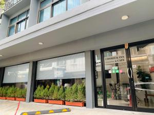 a store front of a building with windows and plants at Udomsuk Inn & Cafe Since 2019 - BTS Udomsuk in Bangkok