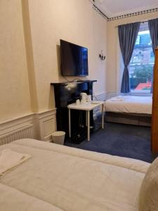 um quarto de hotel com uma cama e uma secretária com uma televisão em Pilrig St Rooms em Edinburgo