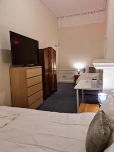 a bedroom with a bed and a desk with a television at Pilrig St Rooms in Edinburgh