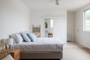a white bedroom with a bed with blue pillows at Saltwood in Bridport