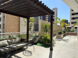 d'une terrasse avec un canapé et des chaises sur un balcon. dans l'établissement Apartamento Top, à Fortaleza
