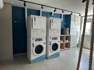 - deux lave-linge dans une buanderie aux murs bleus dans l'établissement Apartamento Top, à Fortaleza