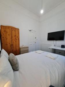 um quarto com uma grande cama branca e uma televisão na parede em Pilrig St Rooms em Edimburgo