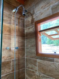une salle de bain avec douche et fenêtre dans l'établissement Chalé Vale das Minas Gerais, à Camanducaia