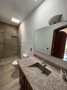 ein Badezimmer mit einem Waschbecken, einem WC und einem Spiegel in der Unterkunft Casa Serena - Casa de Huéspedes in Guadalajara
