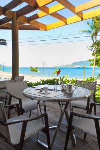 a table and chairs with the beach in the background at Abayomi Hotel in Ilhabela