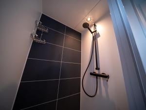 y baño con ducha y pared de azulejos negros. en Luxury houseboat with beautiful views over the Mookerplas, en Middelaar