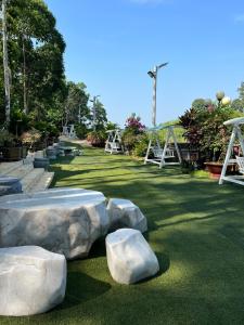un parc avec des rochers dans l'herbe et une aire de jeux dans l'établissement Cat Tien River Lodge, à Cat Tien
