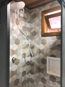 uma casa de banho com uma cabeça de chuveiro numa parede de azulejos em Residência Vô José - Casa 02 em Pomerode
