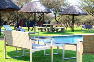 a group of chairs and umbrellas next to a pool at Bradbury Game Lodge and Function Venue in Polokwane