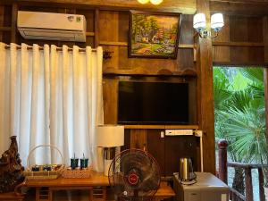 a living room with a television and a table with a fan at Cat Tien River Lodge in Cat Tien