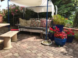a patio with a couch under an umbrella and flowers at Escapade dans la campagne toulousaine in Beaumont-sur-Lèze