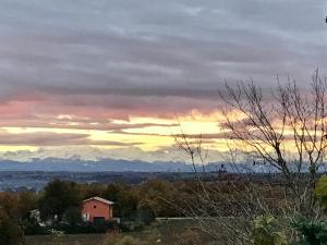 a sunset with a house and mountains in the background at Escapade dans la campagne toulousaine in Beaumont-sur-Lèze