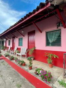 ein rosafarbenes Haus mit weißen Stühlen und Blumen in der Unterkunft Hostal Voyager La Villa de Los Santos, Panama in Los Santos