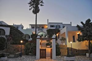 a building with a door in a courtyard with a palm tree at Porto Vlastos in Agios Ioannis
