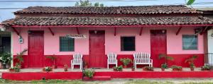 a pink house with white chairs in front of it at Hostal Voyager La Villa de Los Santos, Panama in Los Santos