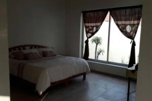 um quarto com uma cama e uma janela com uma palmeira em Villa Colibri Casa Vacacional alberca asador jardín 15 huéspedes em Temixco