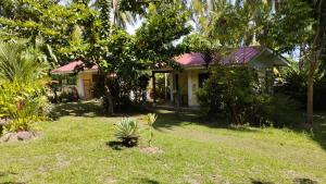 a small house in a yard with grass and trees at ACACIA'S Cottages mit Starlink Wifi in Mambajao