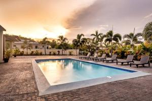 a swimming pool with chairs and a house at Villa Camilla in Ocho Rios