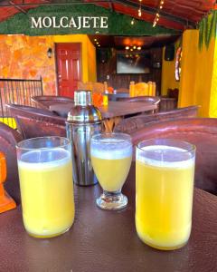 Dois copos de sumo de laranja sentados numa mesa. em Posada Siete Nogales Tecozautla alojamiento con baño compartido em Tecozautla