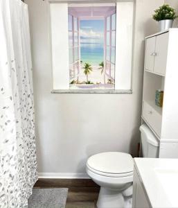 a bathroom with a toilet and a window with the beach at Large 3 Bedroom Home 12 Minutes to Beach in Clearwater