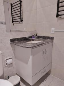 a white bathroom with a sink and a toilet at Riviera de São Lourenço Flat in Riviera de São Lourenço