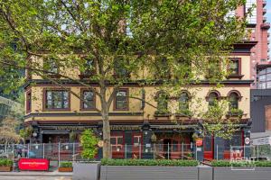 un edificio giallo con un albero di fronte di Melbourne Bourke Street Bliss a Melbourne