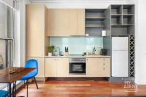 cocina con armarios blancos, mesa y sillas azules en Melbourne Bourke Street Bliss, en Melbourne