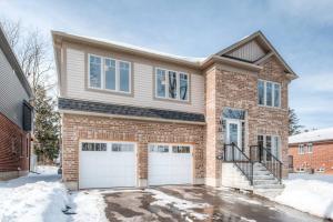 una casa in mattoni con due porte bianche per il garage di Riverside Villa a Kitchener