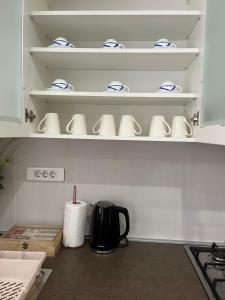 a kitchen with white shelves with cups and a tea kettle at ALOM in Osijek